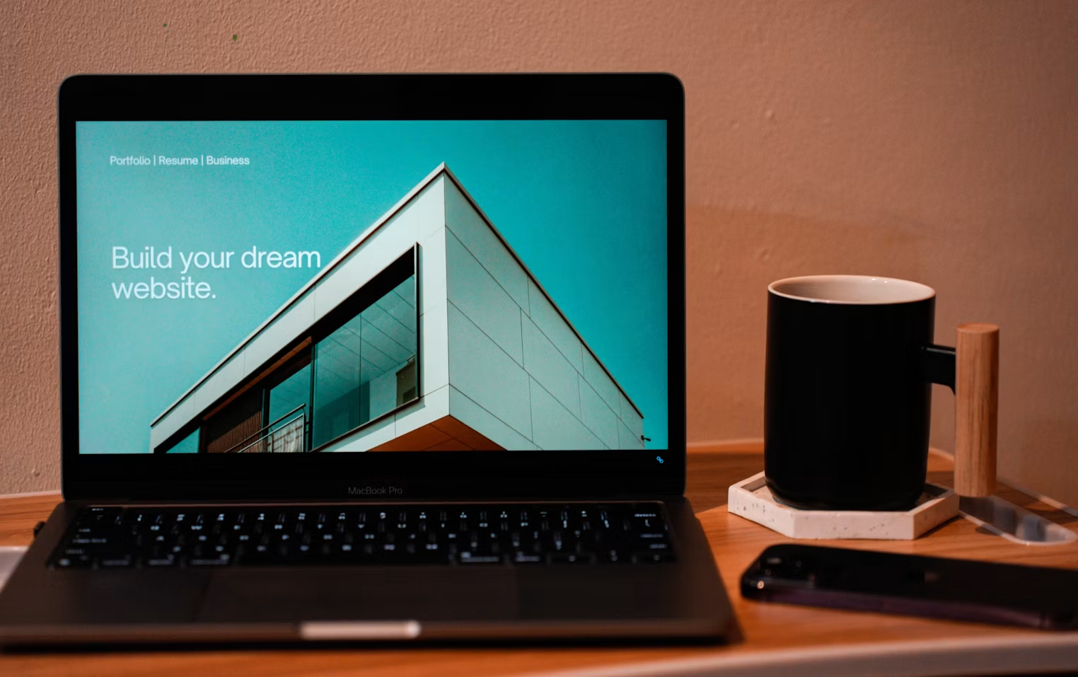 MacBook Pro på trebord som viser en moderne nettside, ved siden av en kaffekopp